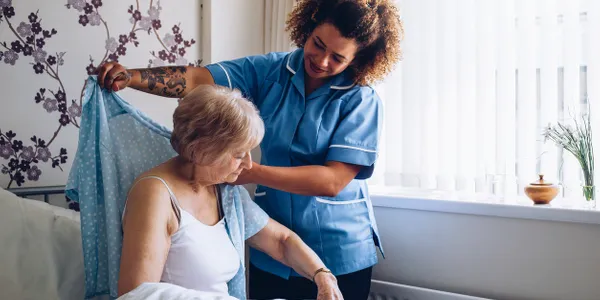 In-home caregiver assisting an elderly woman with dressing and personal care services