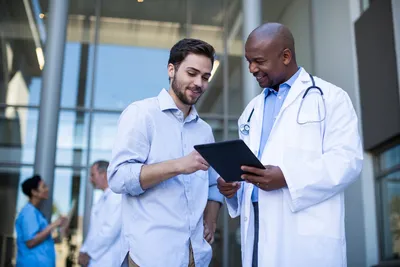Professional doctor discussing health information on a tablet with a patient outside a medical facility