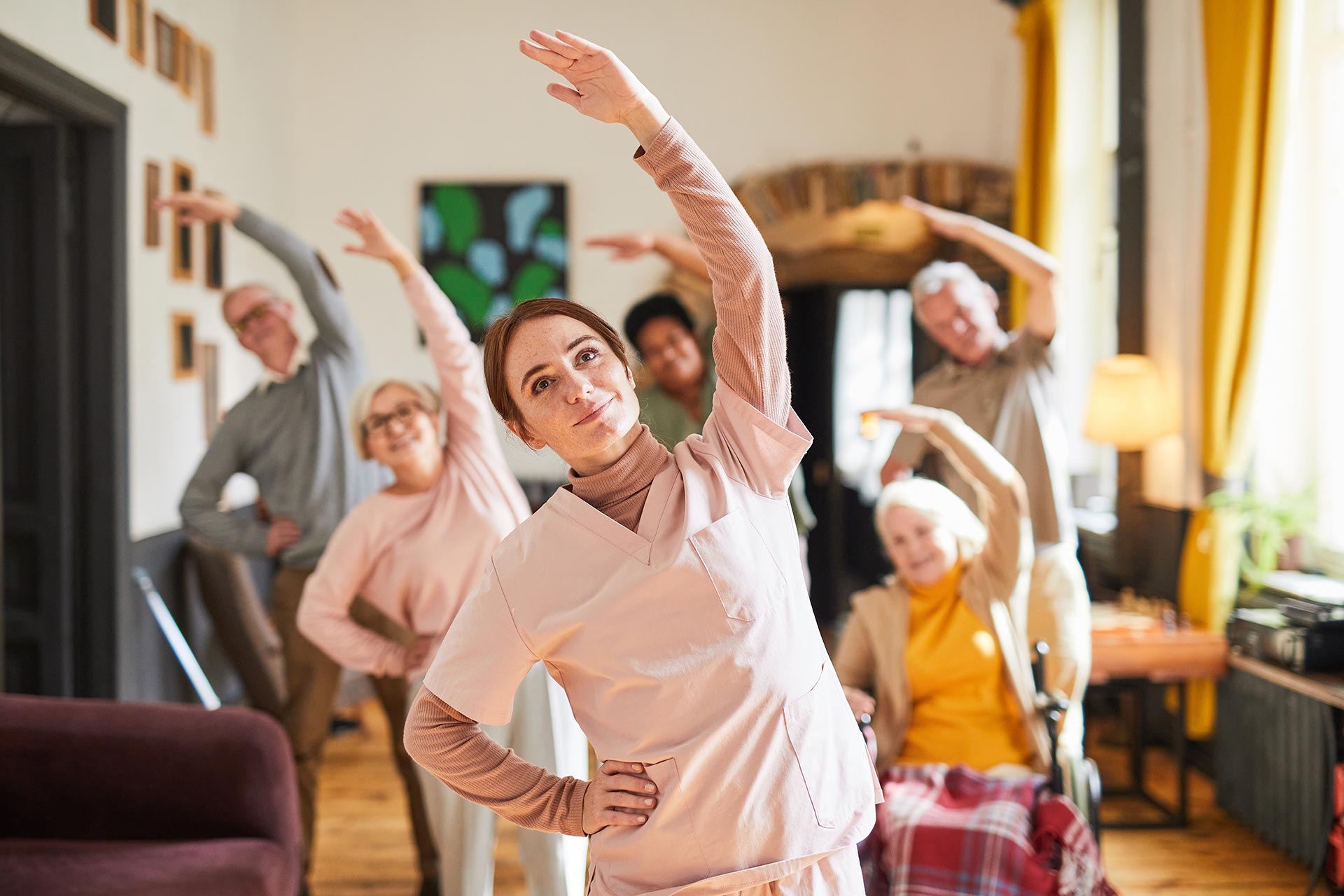 Professional caregiver leading a group exercise session for seniors at home