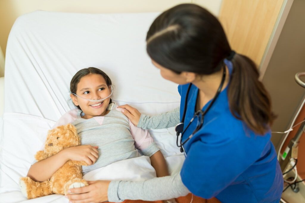 little girl patient holding teddybear while listening healthcare worker hospital bed treatment GAPP Program